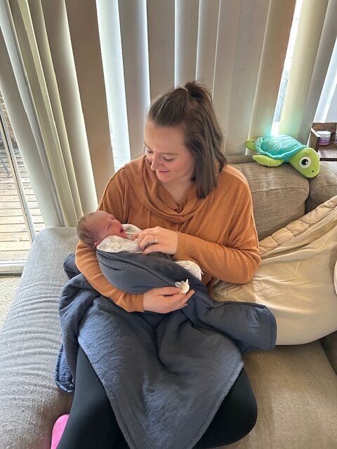 Doula Hannah gently holding a newborn baby, offering comfort and care in a peaceful setting.